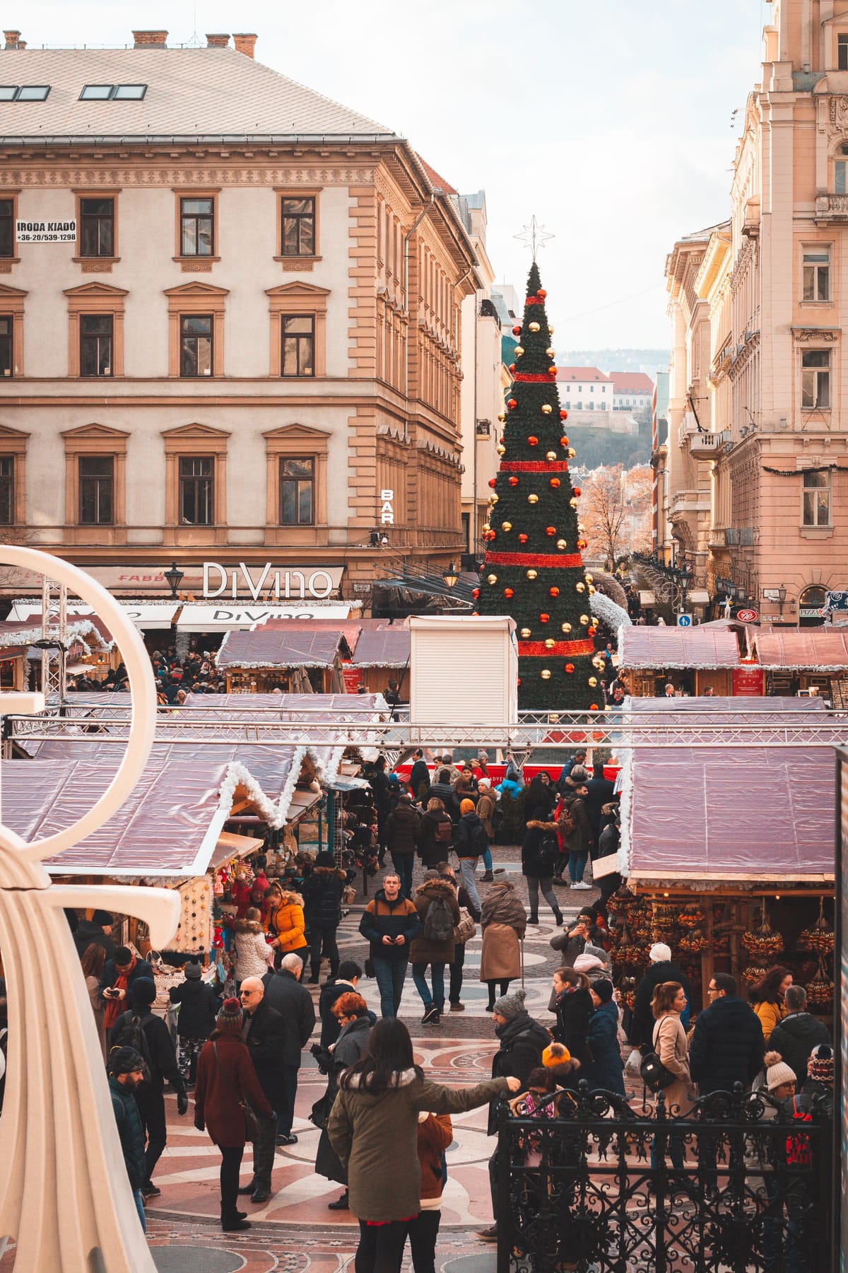 Budapest's Vörösmarty Square Christmas market with a lit Christmas tree and the DiVino wine bar sign