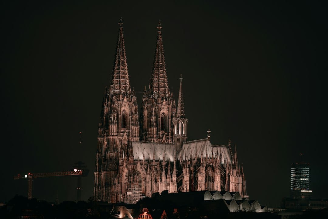 Cologne Cathedral's twin Gothic spires lit up at night above the Christmas market. Photo by Omar Ramadan on Unsplash