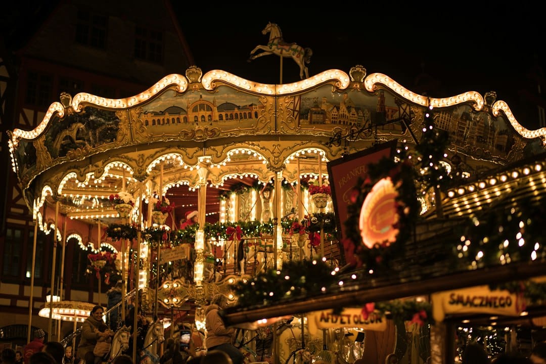 Illuminated carousel at the Frankfurt Christmas Market in Germany, framed by half-timbered houses — a classic European Christmas market scene. Photo by cmophoto.net on Unsplash