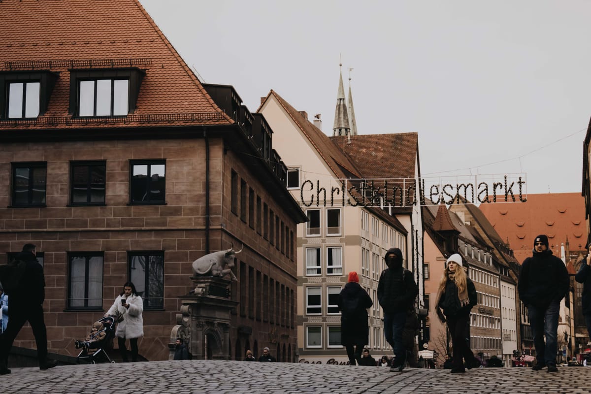 Nuremberg's illuminated Christkindlesmarkt sign with the golden Männleinlaufen figure and Frauenkirche spires behind