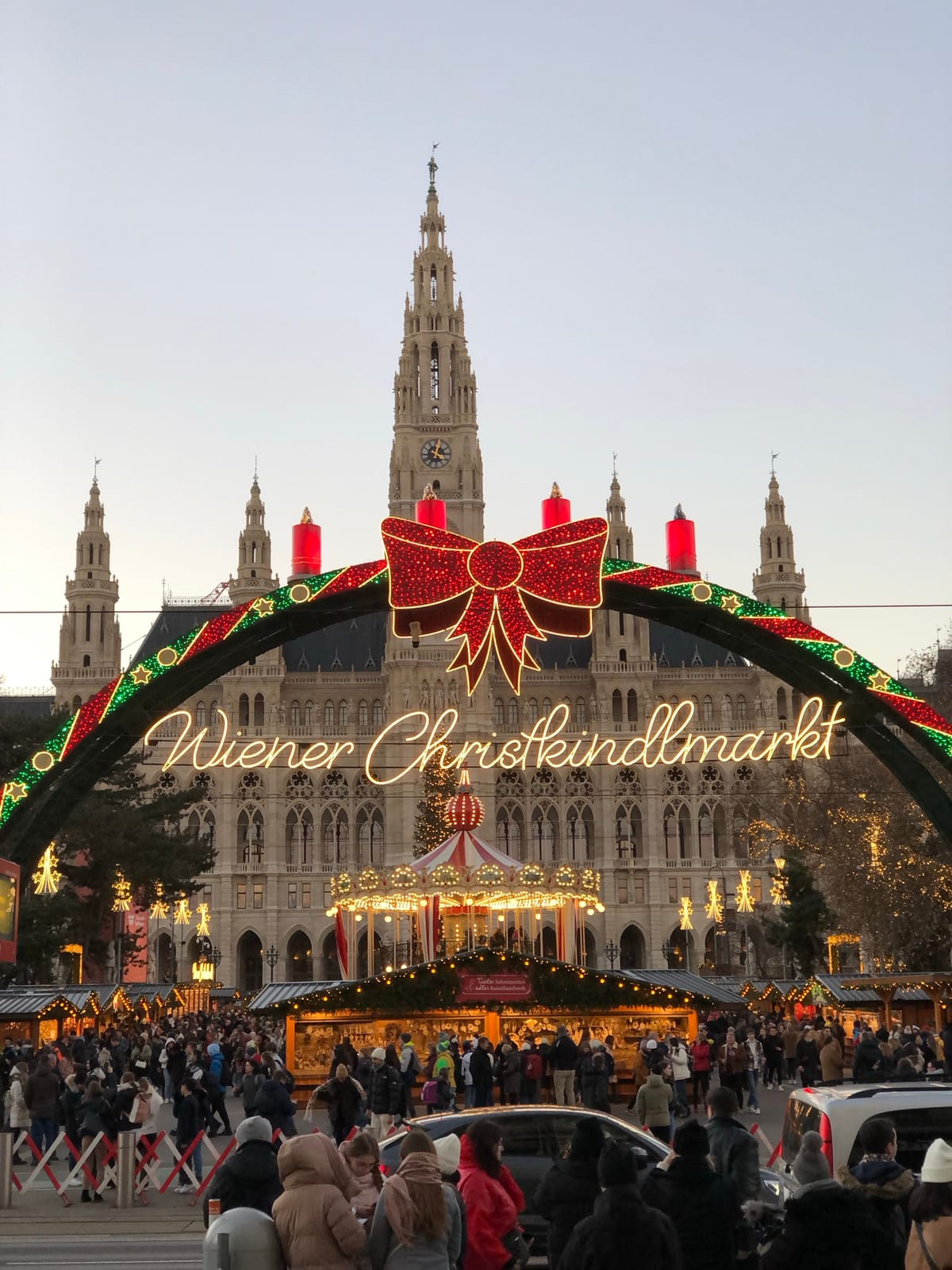 The Wiener Christkindlmarkt sign lit up in front of Vienna's neo-Gothic City Hall (Rathaus) at dusk