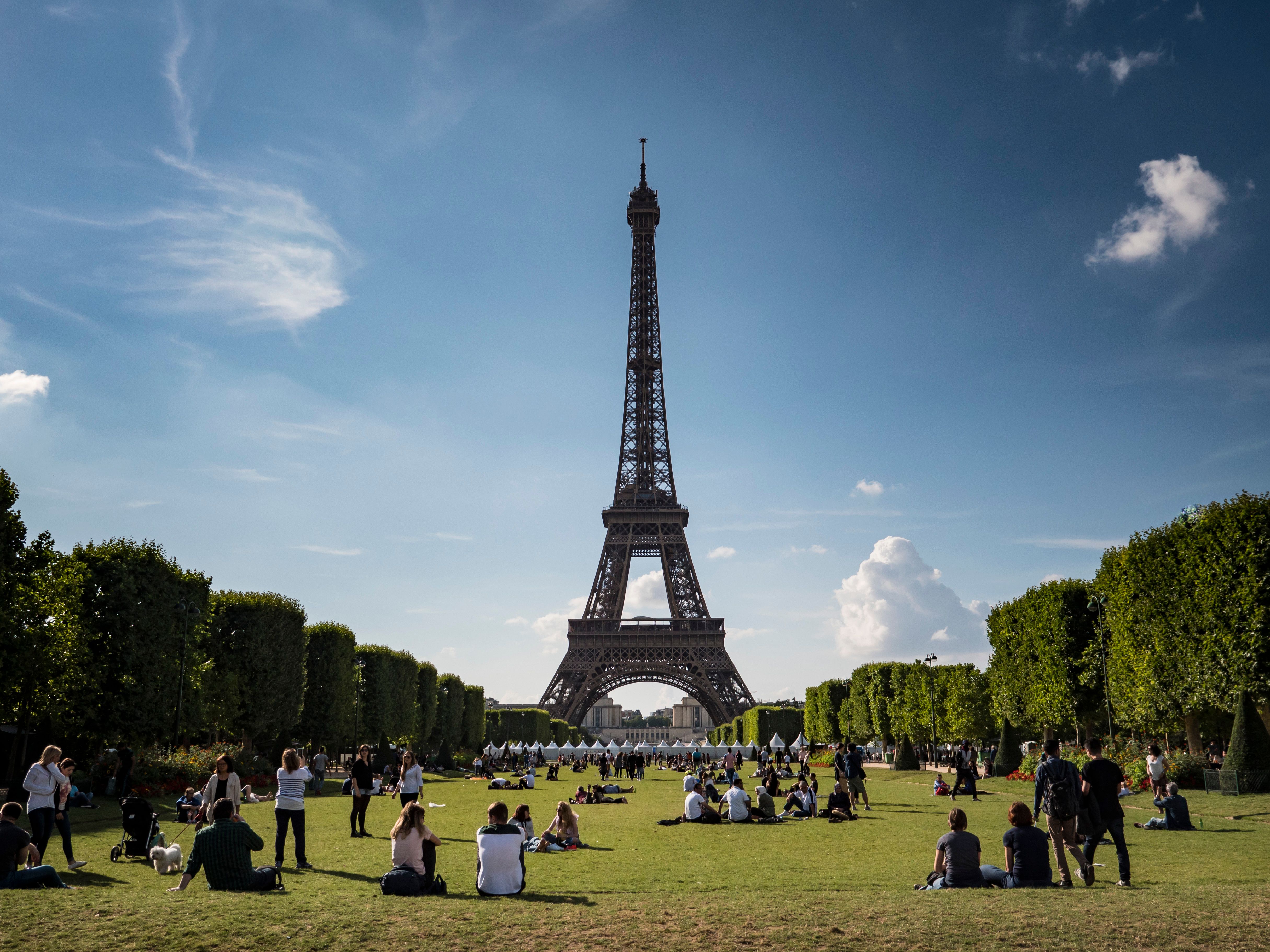 Eiffel Tower in Paris France with travelers relaxing on the grass