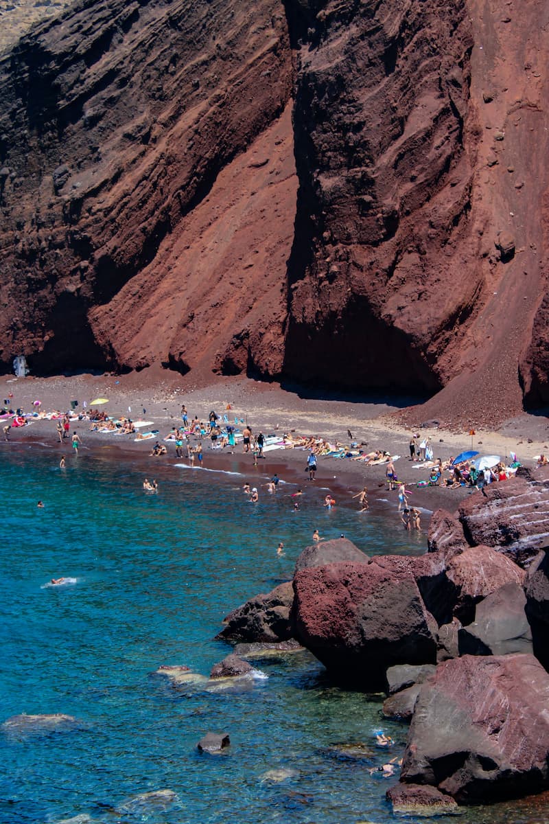 Red Beach's volcanic cliffs and swimmers, Santorini