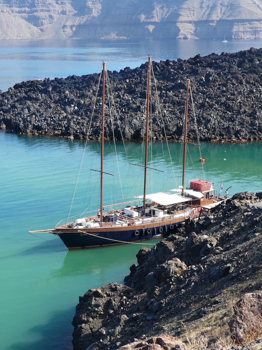 Boat anchored near the volcanic shoreline of Nea Kameni, Santorini