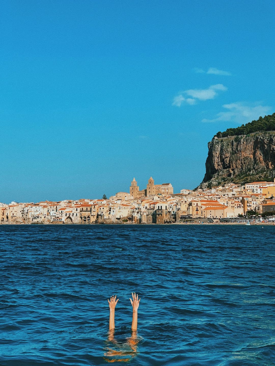 Cefalù's twin-towered Norman cathedral rising above the town, seen from the sea, Sicily. Photo by Anastasiia Rozumna on Unsplash