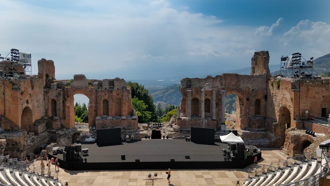 Ancient columns of the Greek Theatre in Taormina framing a view of Mount Etna, Sicily. Photo by Alexis Subias on Unsplash