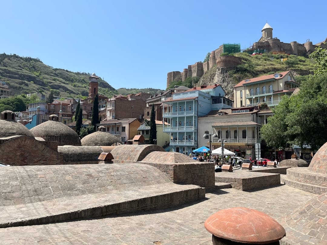 Domed roofs of the Abanotubani sulfur bathhouses in Tbilisi's Old Town, with Narikala Fortress on the hill behind
