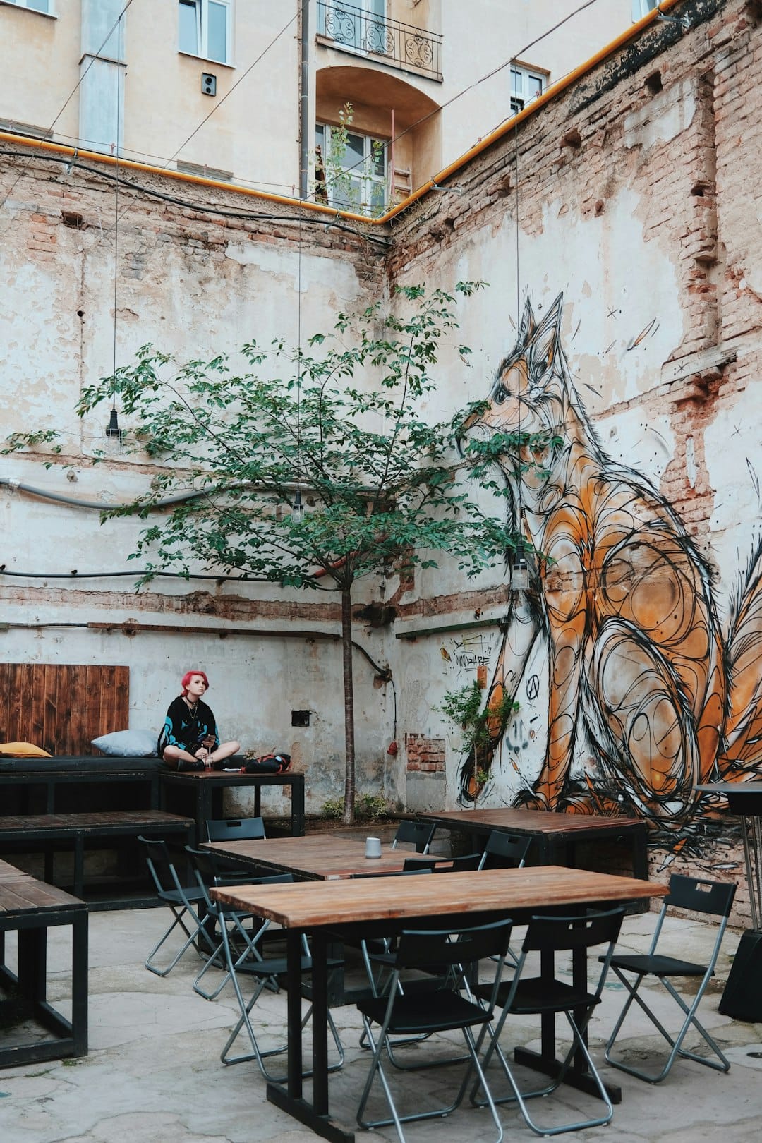 Courtyard of Fabrika, a former Soviet factory turned creative hub in Tbilisi, with street art and café tables. Photo by Aleksey Cherenkevich on Unsplash